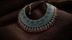 a bold, ornate silver bedouin necklace adorned with turquoise and carnelian stones, displayed against a traditional woven fabric backdrop.